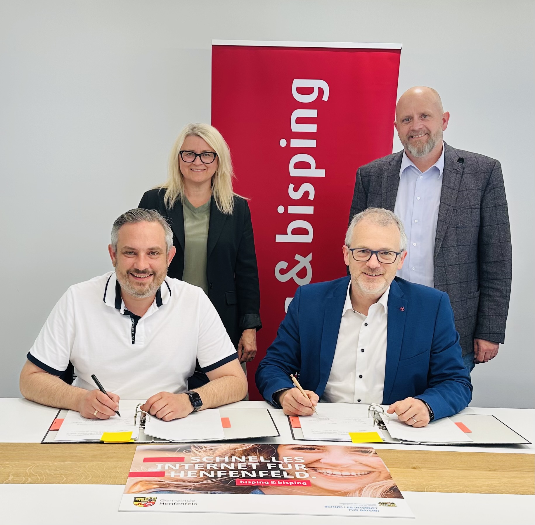 Vertragsunterzeichnung für den Glasfaserausbau in Henfenfeld: Bürgermeister Markus Gleißenberg und Johannes Bisping unterzeichnen die Kooperationsvereinbarung, begleitet von weiteren Projektbeteiligten vor dem Bisping & Bisping Banner.
